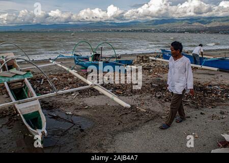 Palu City, Indonesia. 03rd Jan, 2020. A fisherman walks passed an anchored boat.High waves in the waters of Palu Bay forced Hundreds of fishermen in the village of Lere to anchor their boats. According to the Palu Meteorology, Climatology and Geophysics Agency (BMKG) the waves reached two meters to three meters, considered quite dangerous for fishermen. Credit: SOPA Images Limited/Alamy Live News Stock Photo