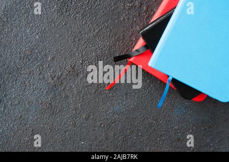 Stack of colorful notebooks for writing or books on dark background. Stock Photo