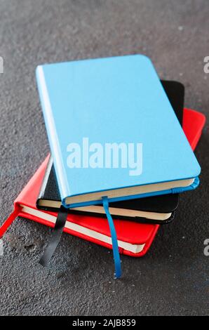 Stack of colorful notebooks for writing or books on dark background. Stock Photo