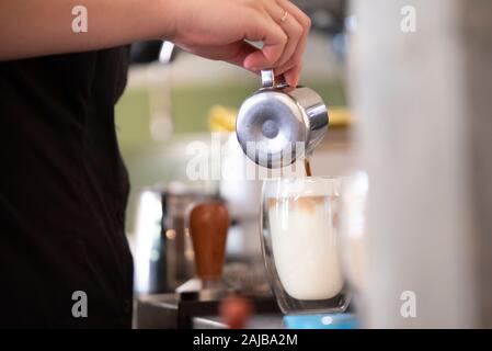 Action image of making of milk coffee pouring milk into glass Stock Photo