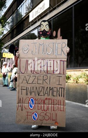 Turin, Italy - 19 July, 2019: A climate activist shows a protest cartel against Jean Pierre Mustier, CEO of Unicredit bank, wearing mask inspired by the Money Heist series ('La casa de papel') broadcast by Netflix. Climate activists from Fridays for Future and Extinction Rebellion groups protest against investments by banks in fossil fuels. Credit: Nicolò Campo/Alamy Live News Stock Photo