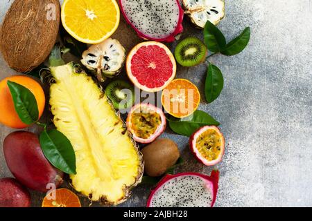 Exotic asia fruit background. Assorted ripe juicy tropical summer seasonal fruits on a gray stone background. Top view flat lay background. Stock Photo