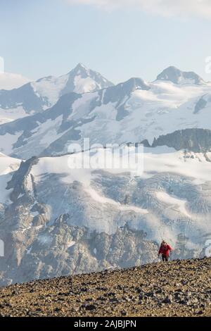Small hiker juxtaposed against large glaciated mountains Stock Photo