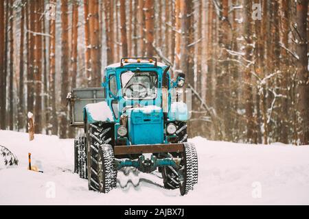 Old Tractor On Country Forest Road In Winter Snowy Day. Stock Photo