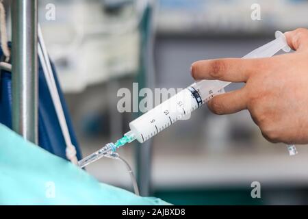 Nurse injecting a drug through an infusion system Stock Photo