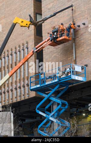 Workers Attaching Awning to a Murray Hill Office Building on cherry Pickers, NYC, USA Stock Photo