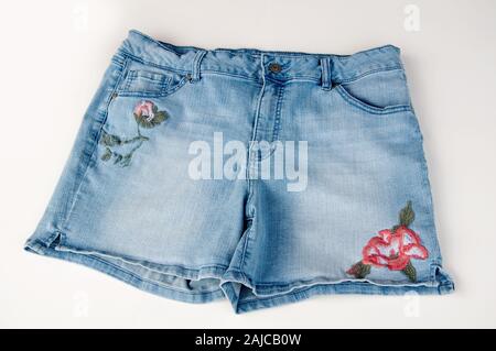 Jean shorts with floral embroidery isolated on a light background.  Women's summer fashion casual style blue denim cutoffs. Stock Photo