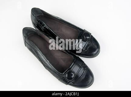 Pair of black patent leather womens shoes isolated on a light background.  Shiny black leather has a button and strip details, casual fashion accessor Stock Photo