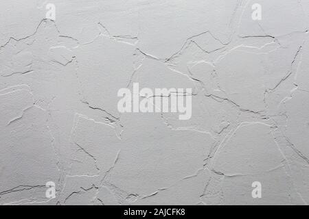 Abstract white unobtrusive background and texture. A plaster wall with old cracked layer under new one. Top-down light direction. Stock Photo