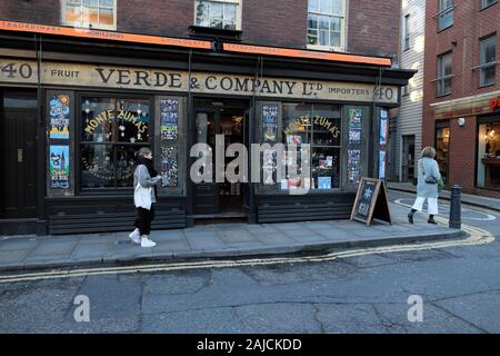 Person walking in the street outside Verde & Company deli shopfront exterior at Christmas time in Spitalfields East London E1 England UK  KATHY DEWITT Stock Photo