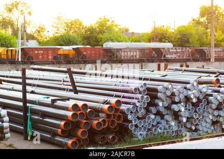 Metal rolling. Pipes folded in a railway warehouse are being prepared for shipment. The concept of metalworking and heavy industry. Stock Photo