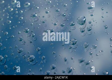 Beaded water drops on glass with cloud reflection. Stock Photo