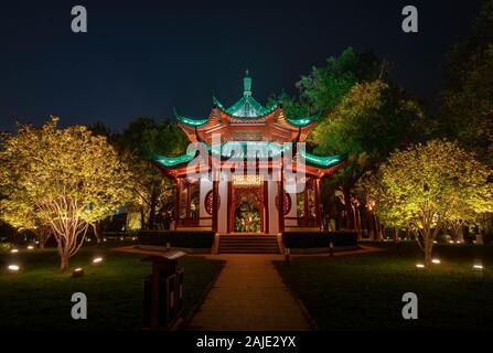 WUHAN, HUBEI / CHINA - NOV 20 2019: Night view of  Chinese Pavillion with light decoration at East Lake and city skyline on background, Wuhan, Hubei,