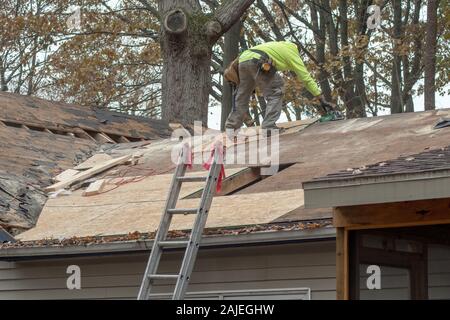 A worker cuts sheets of plywood to repair a rooted roof on an old home Stock Photo