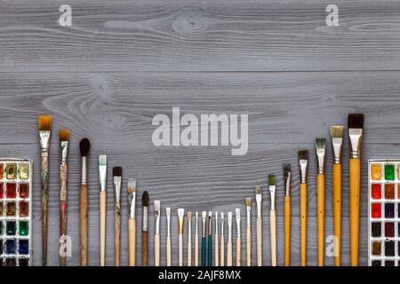 Paintbrushes set and watercolor paints on grey wooden table Stock Photo
