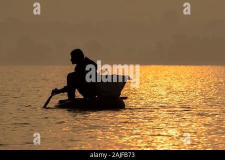 Bichhiya / India / November 29, 2019 - Silhouette photo Indian fisherman is fishing in the pond by sitting in a tube. Stock Photo