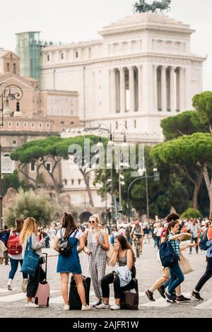 Rome, Italy - October 21, 2018: Young Women Tourists With Carrying Suitcases Standing Near Altar Of The Fatherland On Piazza Venezia. Stock Photo