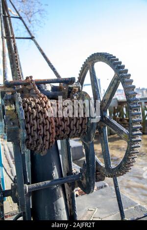 Old Wheel Winch with Rusted Chains alongside River Thames in London UK Stock Photo