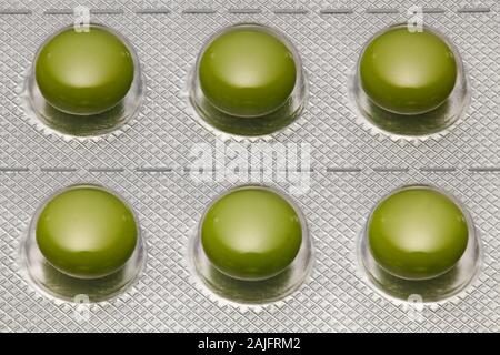 Green tablets in blister pack arranged with beautiful pattern. Global healthcare concept. Antibiotics drug resistance. Antimicrobial capsule pills. Ph Stock Photo