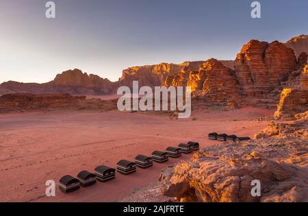Wadi Rum desert, Jordan. Beautiful aerial view of bedouin camp at sunset from above with tents lined up and red rock formations. Panoramic landscape Stock Photo