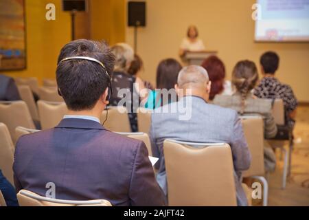 Unrecognizable man using headphones for translation during video conference . bald security guard with the headset to control people . heated debate Stock Photo