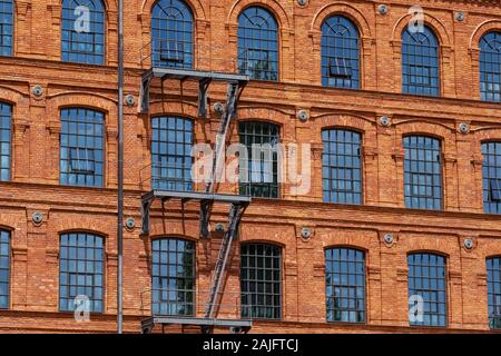 Red brick classic industrial building facade with multiple windows background.  Stock Photo