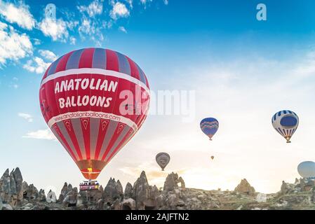 Hot air balloons filled with tourists lifting off during early morning flights over the fairy chimneys of Cappadocia near Goreme, Turkey Stock Photo
