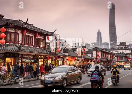 Shanghai, China: Street scene in old town with traditional Asian buildings, people traffic cars motorbikes and Shanghai Tower skyscraper Stock Photo