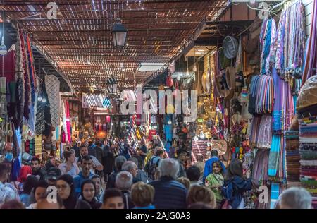 Marrakech, Morocco: People and tourists strolling, booths and stalls in alley nearby Jemma Dar Fna, souk market in Marrakesh medina, crowded bazaar Stock Photo