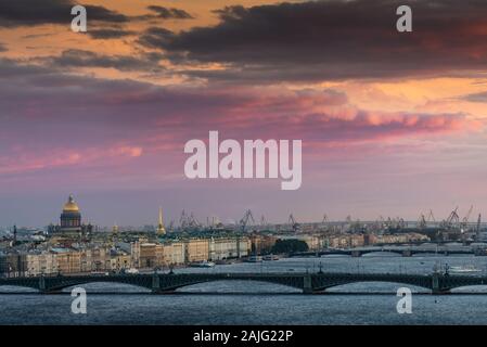 Aerial view: Neva river and Saint Petersburg cityscape: Troitsky bridge, Winter Palace, Saint Isaac's Cathedral, and port cranes in the distance Stock Photo