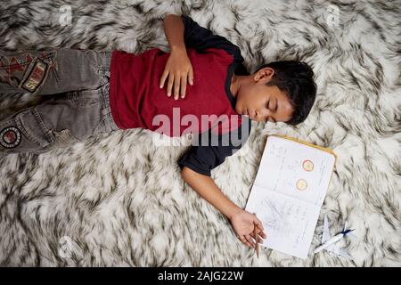 Schoolboy sleeping while doing homework at home Stock Photo