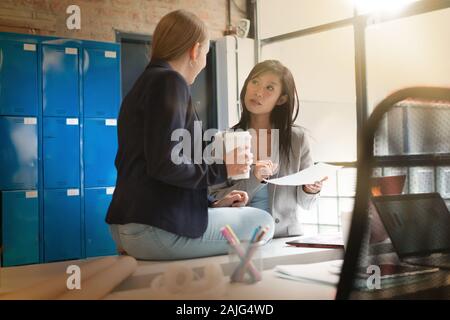 Two female coworkers discussing presentation ideas in modern office Stock Photo