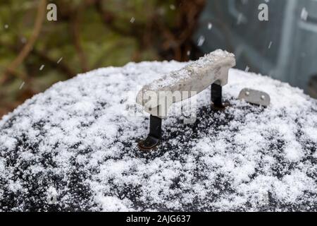 Kettle drum barbecue covered in snow while it is snowing in a UK garden Stock Photo