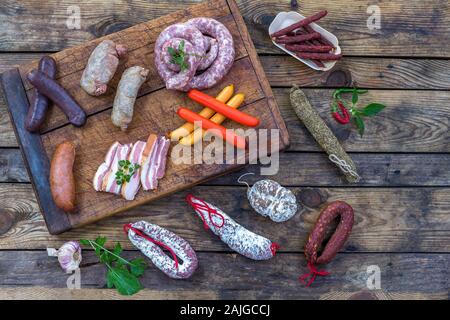 Selection of french raw charcuterie board, with arugula leaves and dry sausage over a wooden background Stock Photo