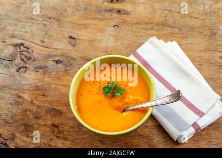 Curried carrot soup with cream and fresh herbs old natural wooden table Stock Photo
