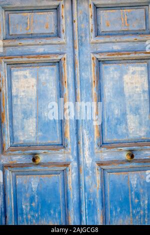 Old blue dirty vintage wooden door with brass handle round. Stock Photo
