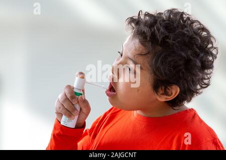 Boy splashes in his mouth with a spray from the pain in her throat. Stock Photo
