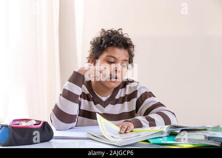Nice boy at room: the boy has a pensive look and he sits at the table, doing homework Stock Photo