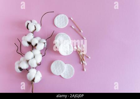 Cotton sticks and pads with fluffy cotton flowers on pink background top view. Flat lay. Copy space for your text. Stock Photo