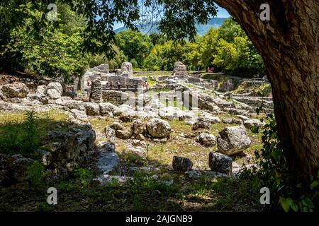 Tourists among stone walls. Beautiful warm spring day and archeological ruins at Butrint National Park, Albania, UNESCO heritage. Travel photography with fresh green flora and clear blue sky Stock Photo