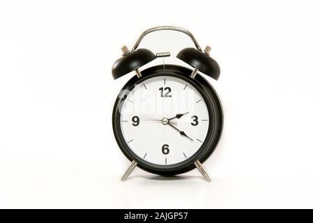 Vintage alarm clock with simple and minimalist design, isolated on white background. Second arm in movement, feeling of passing time, ticking. Stock Photo