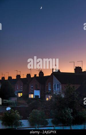 Northampton, UK. Colourful sky just after sunset over the rooftops of the Abington Area of town a fading quarter moon high in the sky. Stock Photo