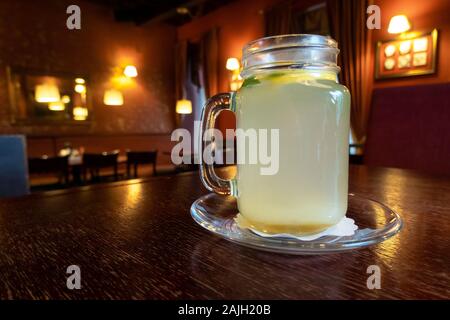 Drinking hot and refreshing ginger tea with slice of lemon in a restaurant. Cup of natural herbal tea on wooden table, warm winter drink Stock Photo
