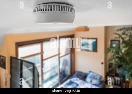 Domestic smoke alarm / battery powered smoke detector on the ceiling in bedroom at home Stock Photo