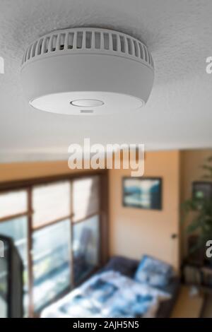 Domestic smoke alarm / battery powered smoke detector on the ceiling in bedroom at home Stock Photo