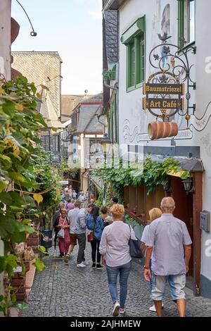 Tourists flock to the narrowest medieval street in Germany called the Drosselgasse, filled with restaurants, shops and bars on the banks of the Rhine Stock Photo