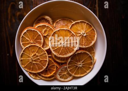 Above shot of festive dried oranges in white bowl on countertop Stock Photo