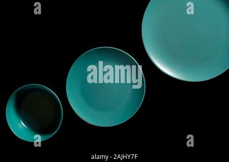 Colored plates of different shapes stand on a black background. Stock Photo