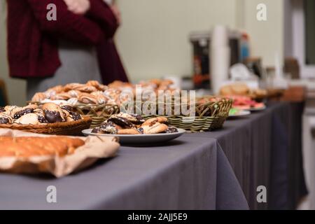 A lot of cookies lie on the grey table. blurred background. holiday or party concept. girl in the background. Stock Photo
