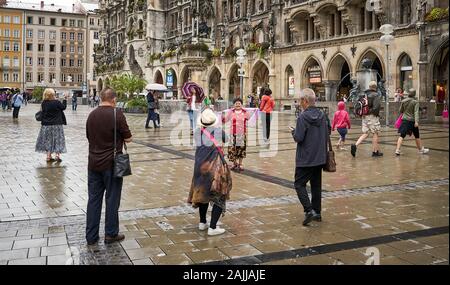 Tourists taking photos of each other and the historic Rathaus with famous Glockenspiel in Marienplatz, downtown Munich, Germany Stock Photo